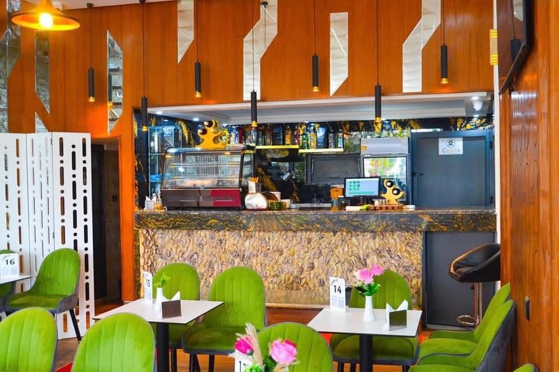 Intérieur du Café Palm d'Or Dakhla — fauteuils velours verts et bar